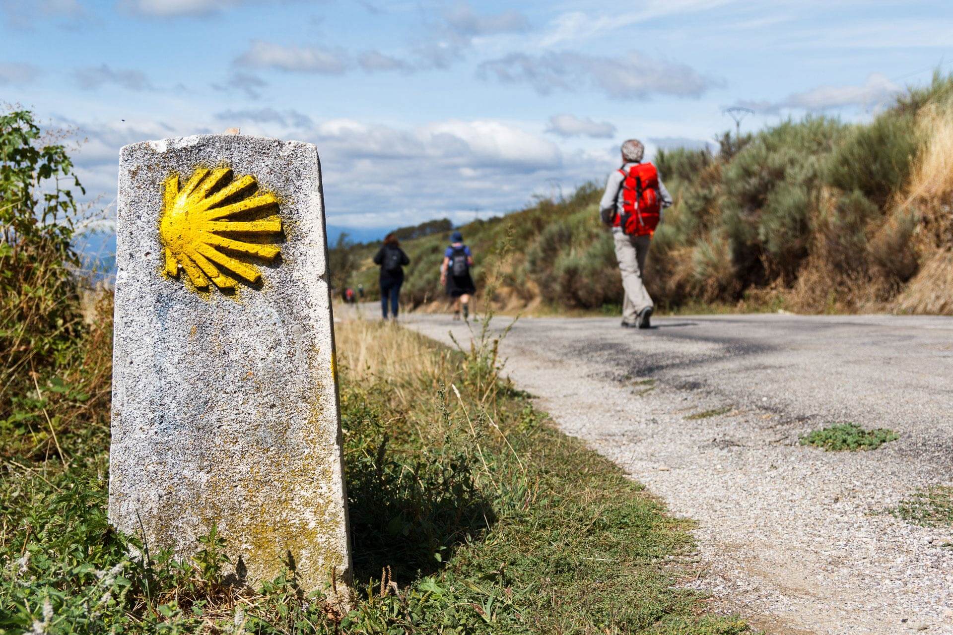 Hikers walking in the background with a trail marker in focus